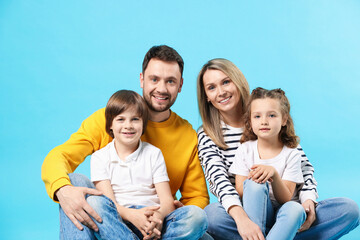 Happy parents and their kids on light blue background © New Africa