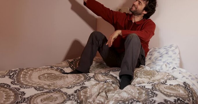 Man sitting on bed taking selfies