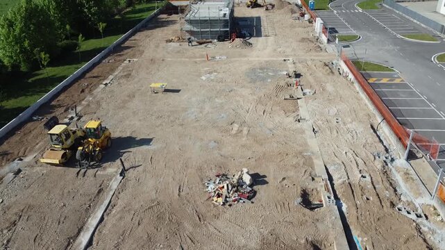 Aerial view of a construction site with heavy machinery and building foundations under development.