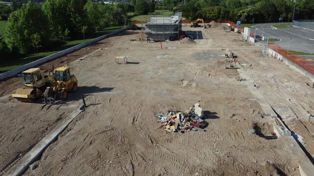 Aerial view of a construction site with heavy machinery and building foundations under development.