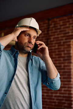 Upset architect talking on mobile phone at construction site.