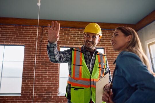 Construction worker talking to female homeowner during renovating process.