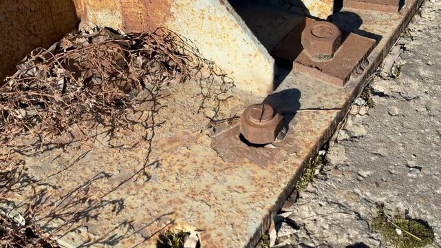 Close-up rusted billboard support base bolted, iron power bracket mounting from below, heavy nuts and bolts corroded, textured