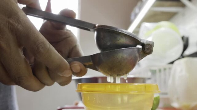 Hands squeezing lime in kitchen, fresh juice preparation