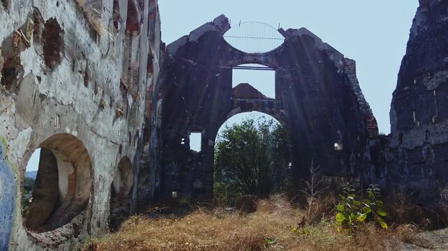 Sunbeams filter through the dilapidated structure of a Hacienda de Coahuixtla building, surrounded by overgrown vegetation, Mexico. Ideal for projects on urban decay or historical exploration.