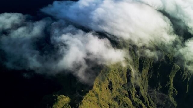 Fast moving clouds over green mountain slopes with cloud cover sweeping across forested ridges creating dramatic atmospheric landscape and dynamic weather sequence aerial drone footage