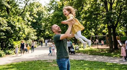 Obraz premium Father lifts daughter in a sunny green park.