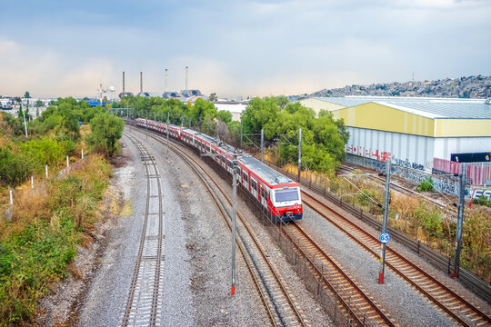 Tultitlan, State of Mexico, Mexico, April 10 2026 Suburban train moving along train tracks with the Lecheria station and a factory in the background at sunset in the State of Mexico