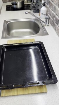 Close-up of hands crumpling baking paper and lining a black baking sheet with it. Preparing the surface before cooking. Video demonstrates a useful culinary trick and kitchen workspace organization.