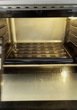 A hand places the vegetable tray into a preheated oven and closes the door. The start of the roasting process. Video demonstrating everyday cooking and home appliance usage.