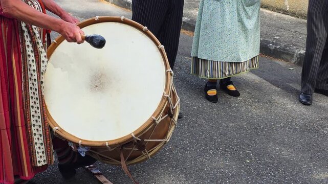 french folkloric group plays a large drum in the street