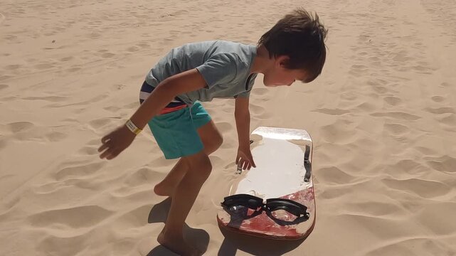 boy finishes sliding down sand dunes in tropical South America gets up and runs back up hill