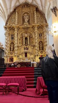 Female tourist using an audio guide while exploring the ornate interior of a historic church in Spain. Vertical travel video with European architecture, cultural tourism, and atmospheric Andalu