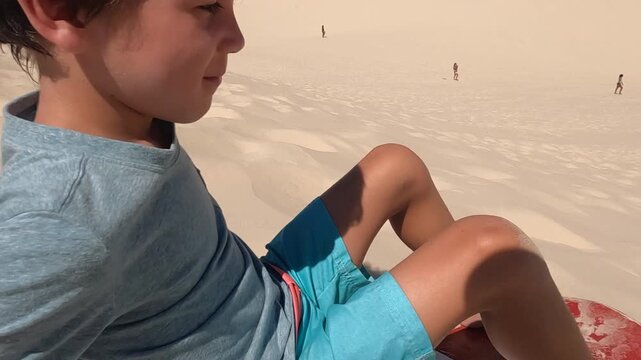 Young boy getting started slidding down sand dunes in South America