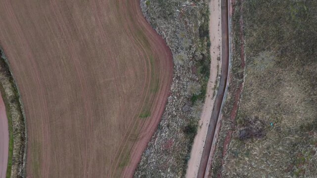 Aerial top down view of a narrow irrigation canal winding through rural farmland