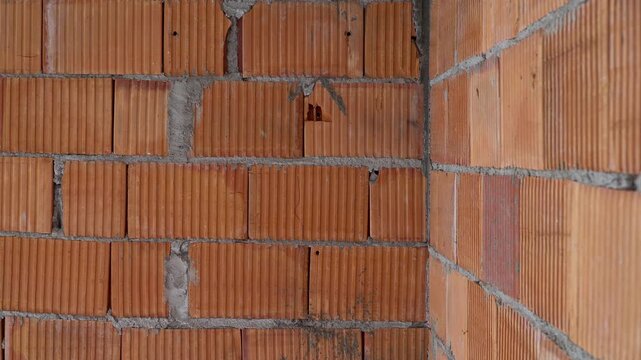 Detailed close-up shot of a wall constructed from red hollow clay blocks at a construction site.