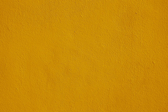 Background of natural yellow gold golden stucco in plaster cement texture lined pattern or stone in colors aged Textured illuminated wall fence surface blend of warm sunny tones backdrop.