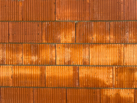 A close-up of a fragment of a wall made of ceramic brick blocks with a horizontal joint (without a vertical joint) as a background