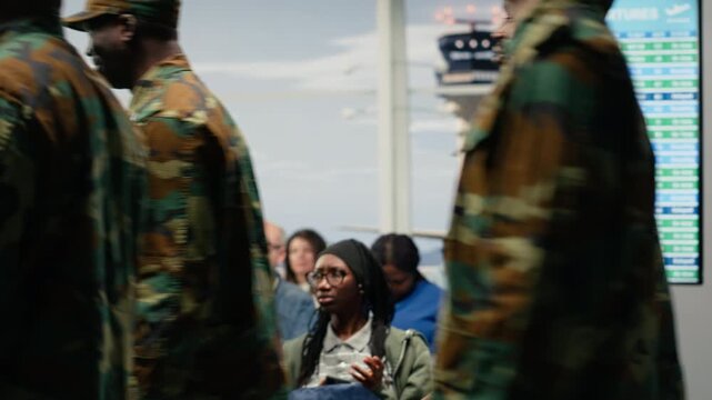 Women curious about army troops presence inside airport terminal, taking pictures with phone. Intrigued girls chatting about military soldiers patrolling aircraft hub waiting area, camera A