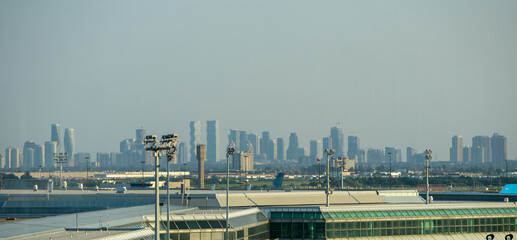 Naklejka premium Distant Toronto Skyline Rising Beyond Airport Infrastructure Under Hazy Summer Atmosphere