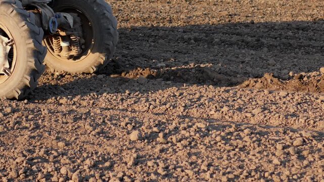 Close up of tractor wheels and harrow cultivating dry soil in field