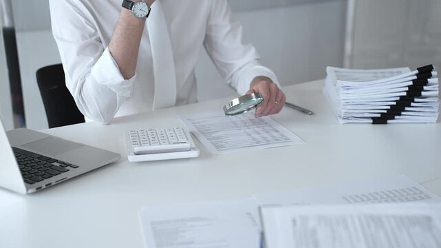 Professional accountant reviewing financial documents and using calculator and laptop to verify figures for audit compliance. Audit and taxes