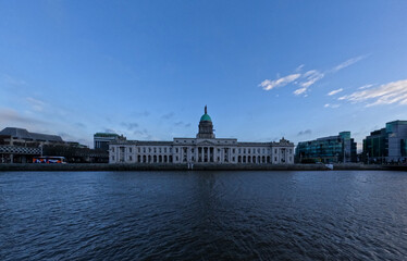 Fototapeta premium Custom House Dublin Ireland Across River Liffey with Neoclassical Architecture and Calm Water Under Clear Sky