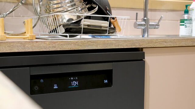 A dishwasher in operation with a glowing digital display and cleaning cycle. Efficient household management, chores, domestic routines, functional kitchen technology 