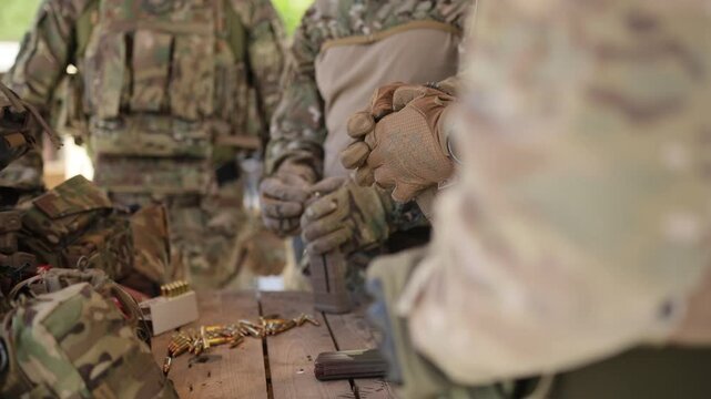Male hands in military uniforms load a magazine with cartridges. Loading a magazine with 7.62 caliber bullets