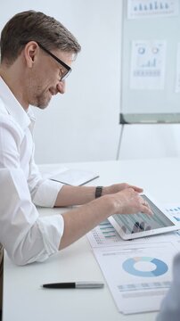 Business professionals reviewing important contract documents, pointing at clauses with a pen, and discussing details during a corporate meeting in an office environment