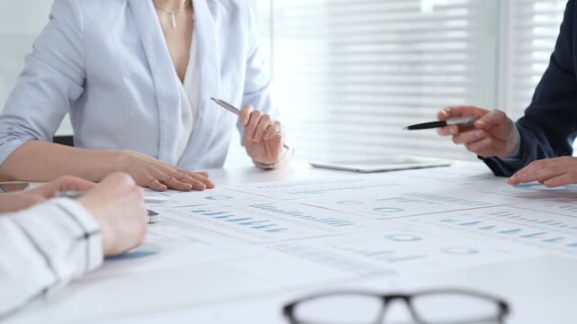 Businesswoman signing important contract documents at a meeting. Confirming agreement and partnership details while colleagues show support