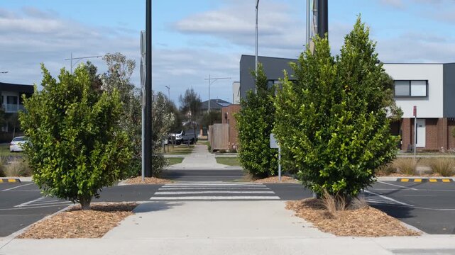 A zebra crossing in a suburban car park featuring a pedestrian walk-through and modern residential housing. Integrated land use, pedestrian safety infrastructure in Truganina, Melbourne Australia