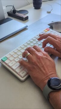 Male hands typing on a computer mechanical keyboard at a desk.