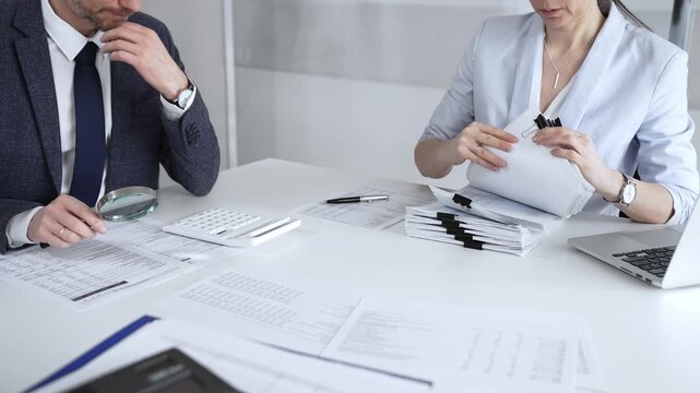 Professional accountant team analyzing corporate financial data, managing paperwork, and preparing tax reports, collaborating on bookkeeping and auditing tasks at a desk. Audit and taxes