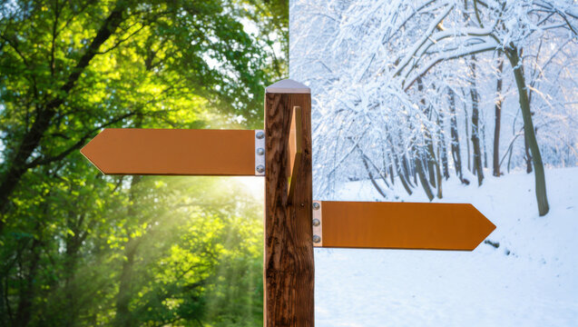 Two blank wooden directional arrows on a post in a split landscape of green summer and snowy winter forest. Choice concept, seasonal contrast, nature direction.