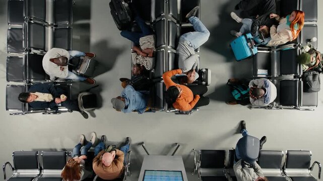 Top down view of passengers in airport resting on benches after delayed flight. Tired travelers sleeping on chairs after losing flight due to airline overbooking, high angle shot