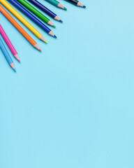 Fototapeta premium colored pencils on blue background with copy space minimal school concept vertical