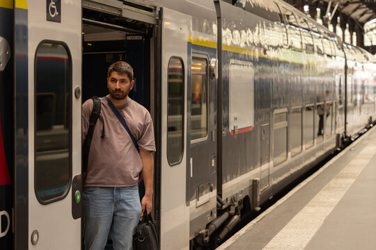 Voyageur descendant d&rsquo;un train en gare avec sac &agrave; dos et bagages