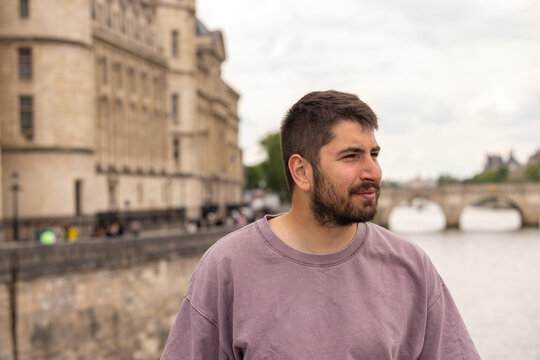 Portrait d&rsquo;un jeune homme souriant au bord de la Seine &agrave; Paris avec architecture historique en arri&egrave;re-plan