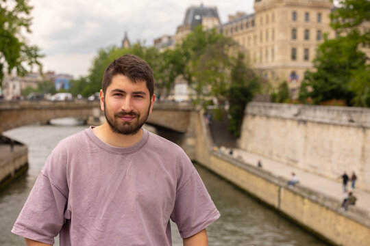 Portrait d&rsquo;un jeune homme souriant au bord de la Seine &agrave; Paris avec architecture historique en arri&egrave;re-plan