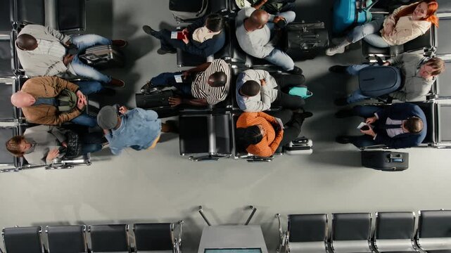 Top down view of men and women in airport holding passport travel documents necessary for international trip. Multiracial passengers with boarding pass enduring long flight layover, high angle shot