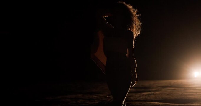 Girl silhouette walking on road illuminated by car headlights at night showcasing a moment of solitude and reflection