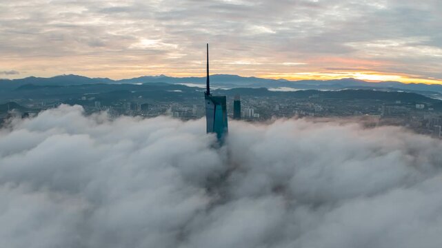 Aerial view time lapse 4k video of Kuala Lumpur city center view during dawn overlooking the city skyline in Federal Territory, Malaysia with epic low cloud glows on sunrise. Zoom out