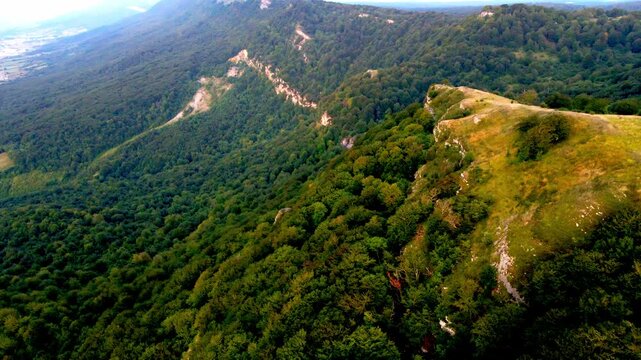 Cinematic drone flight over the mountain spine in Northern Spain. The footage captures a breathtaking perspective of steep rocky cliffs on one side and lush green forests on the other, overlooking a v