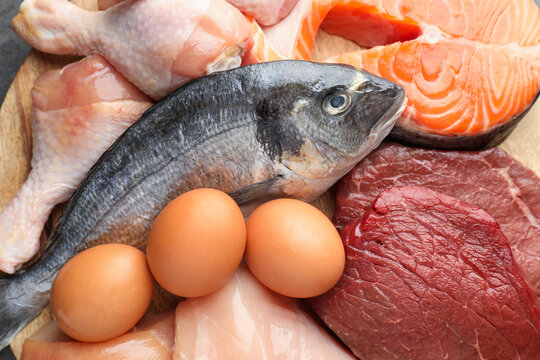 Different types of fresh raw meat, fish and eggs on table, top view