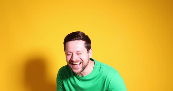 Man laughing and pointing at something on yellow background