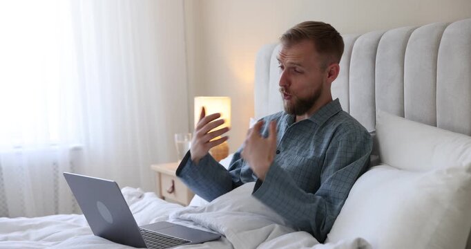 Telemedicine. Man having online consultation with doctor via laptop in bed at home