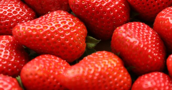 Many fresh ripe strawberries as background, closeup. Camera spinning