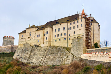 Fototapeta premium Medieval castle on hill with stone walls and scaffolding in overcast sky