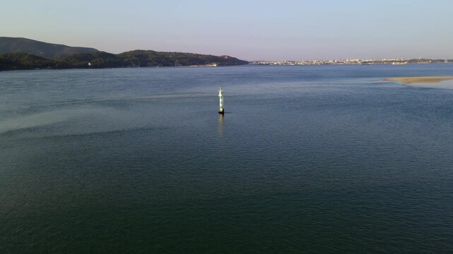 Aerial view of a navigation buoy in the Sado River, Portugal. Drone flying directly over the sea mark with Setubal port in the background.
